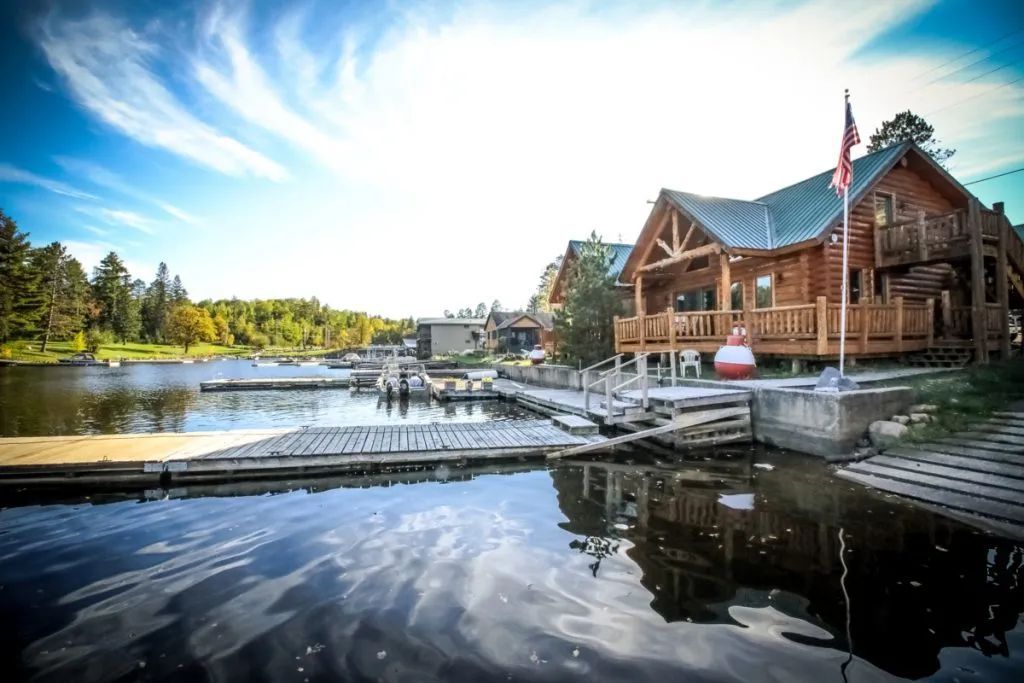 A large log cabin is sitting on top of a body of water.