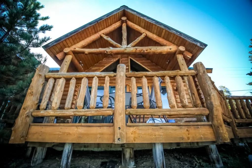 A log cabin with a balcony and a blue sky in the background.