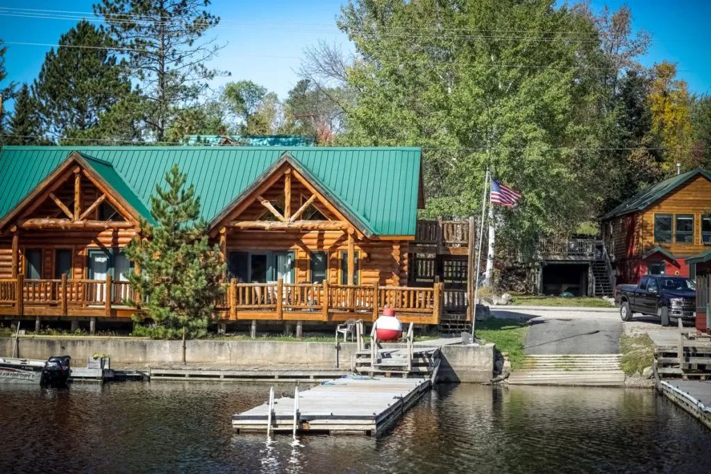 A row of log cabins sitting next to a body of water.