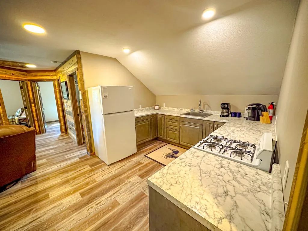 A kitchen with a refrigerator , stove , sink and marble counter tops.