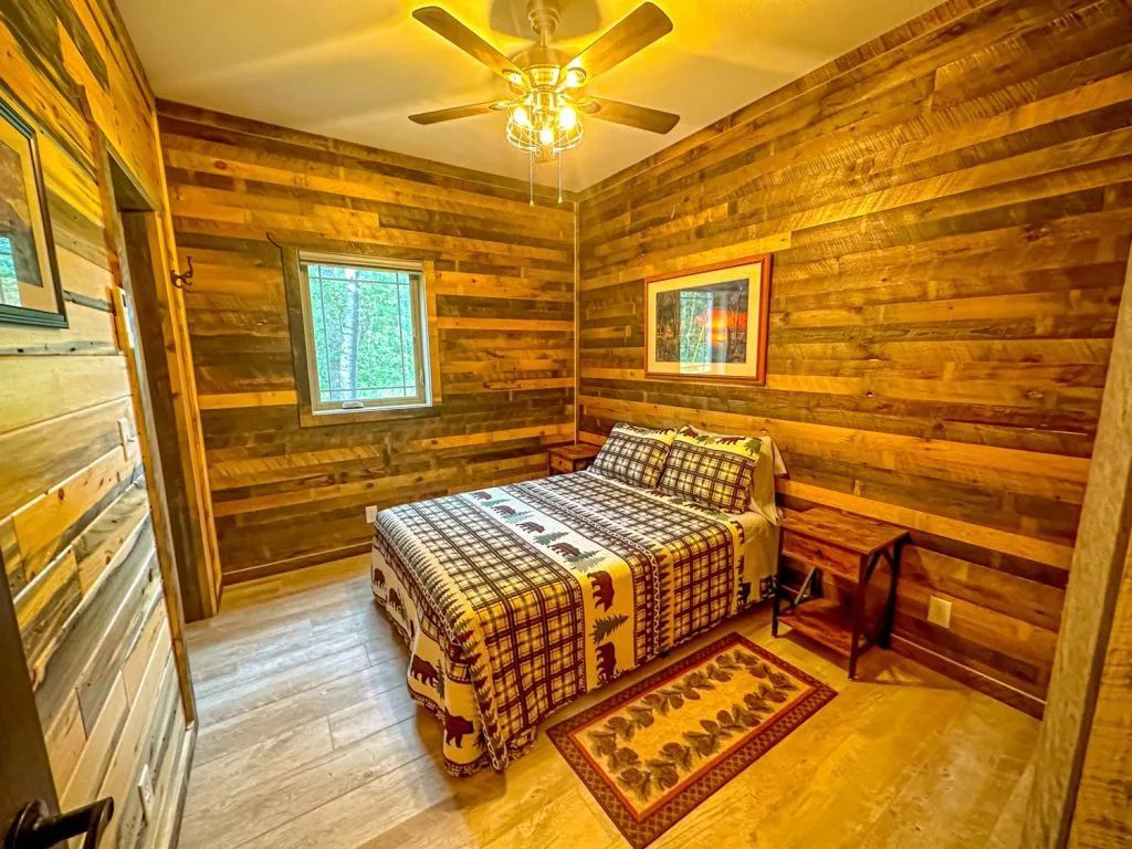 A bedroom with a bed , nightstand , rug and ceiling fan.