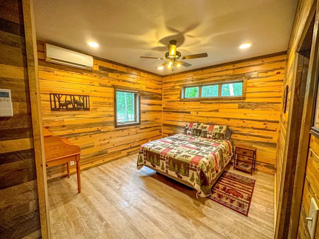 A bedroom in a log cabin with a king size bed and a ceiling fan.
