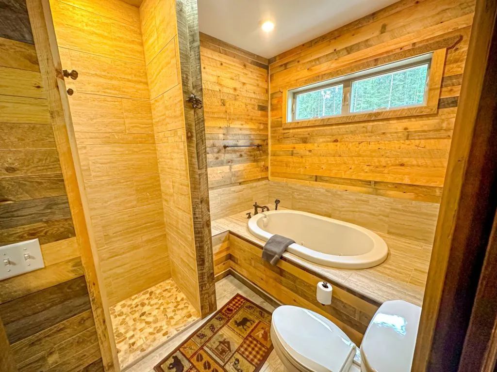 A bathroom with a tub , toilet , shower and wooden walls.
