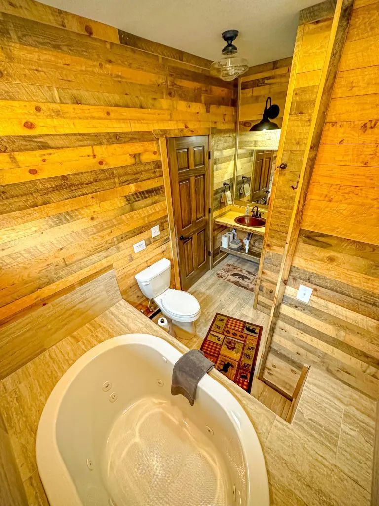 A bathroom with a jacuzzi tub , toilet , sink and mirror.