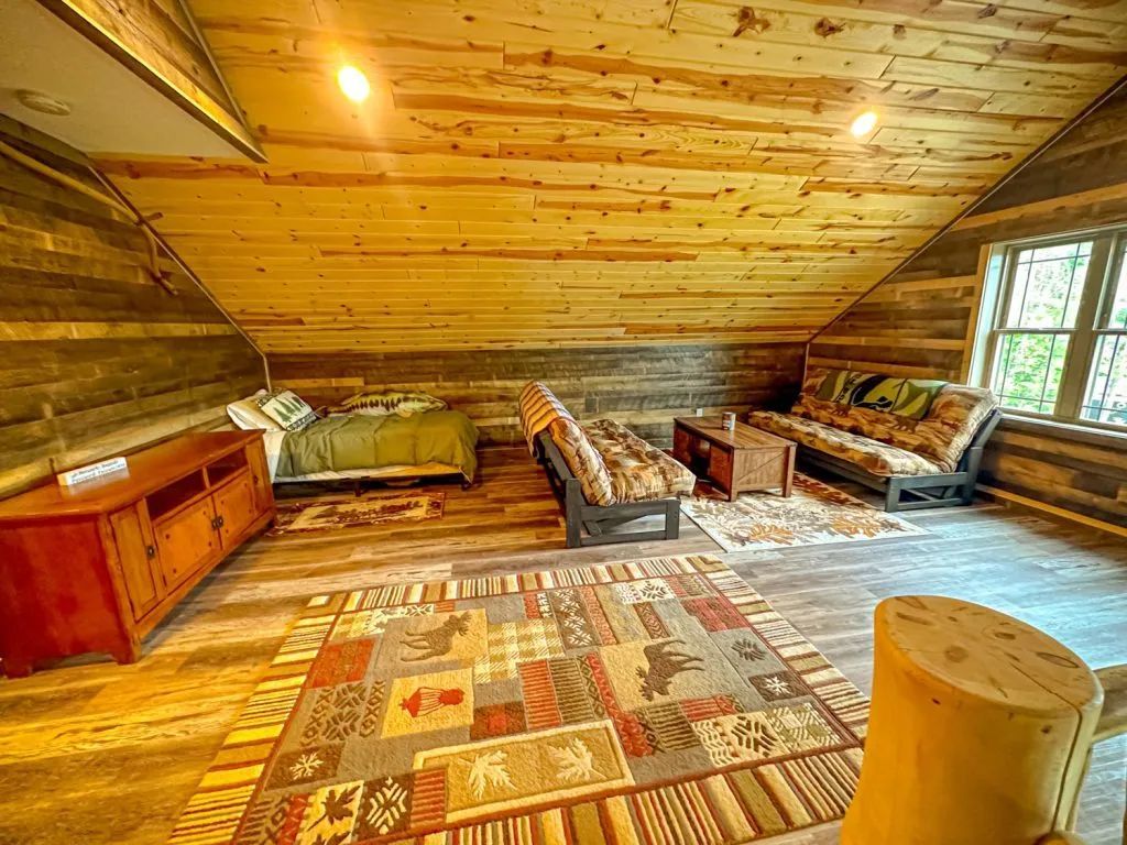 A living room in a log cabin with a bed , couch , and rug.