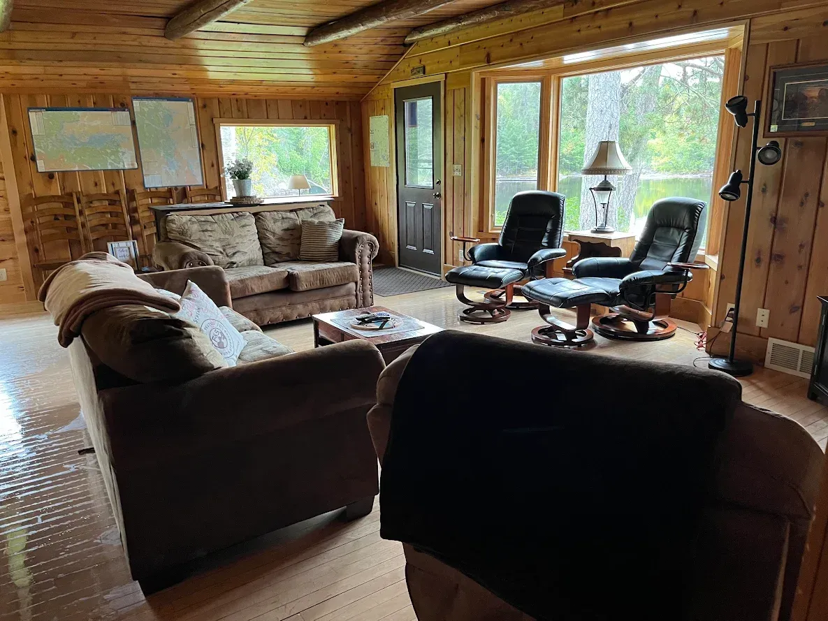 A living room with a dresser , couch , chairs and a television.