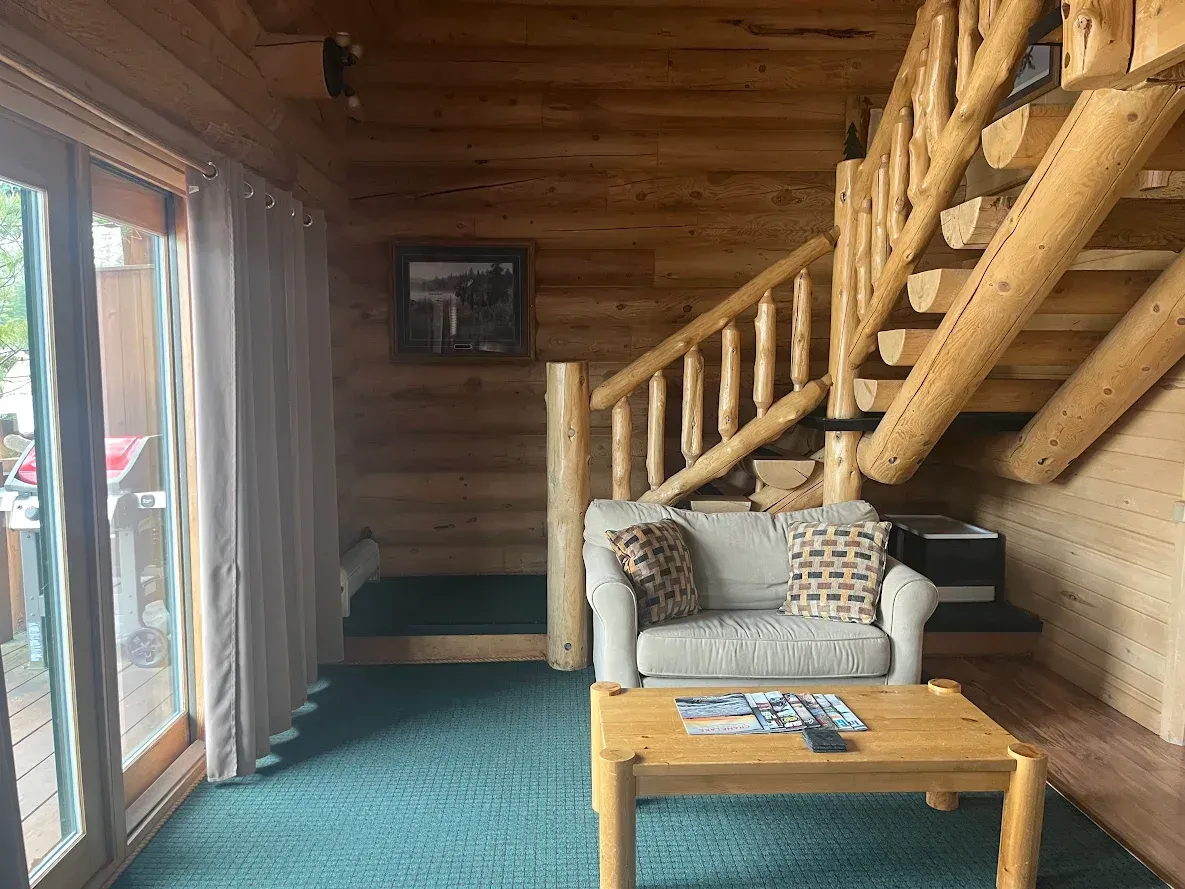 A living room in a log cabin with a couch and bunk beds