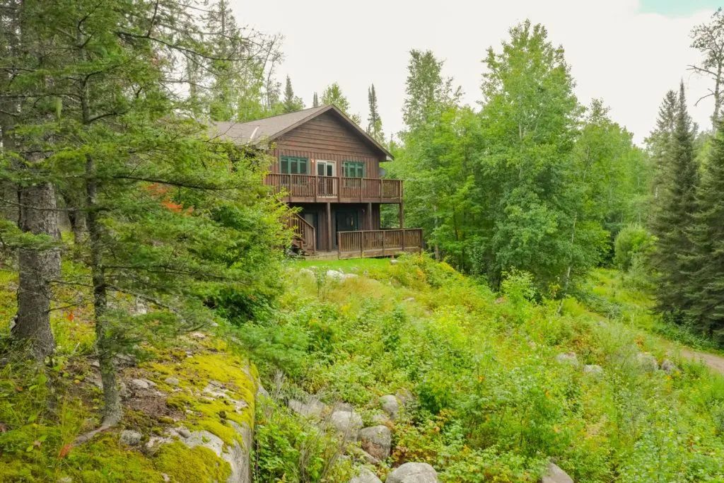 A log cabin is sitting on top of a hill in the middle of a forest.