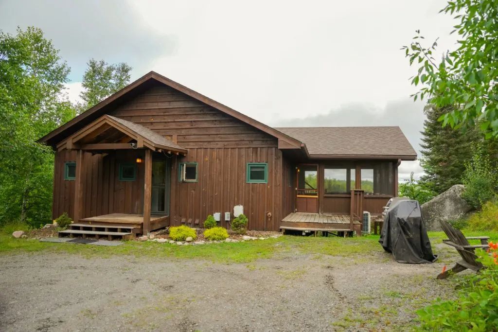 A large wooden house with a porch and a grill in front of it