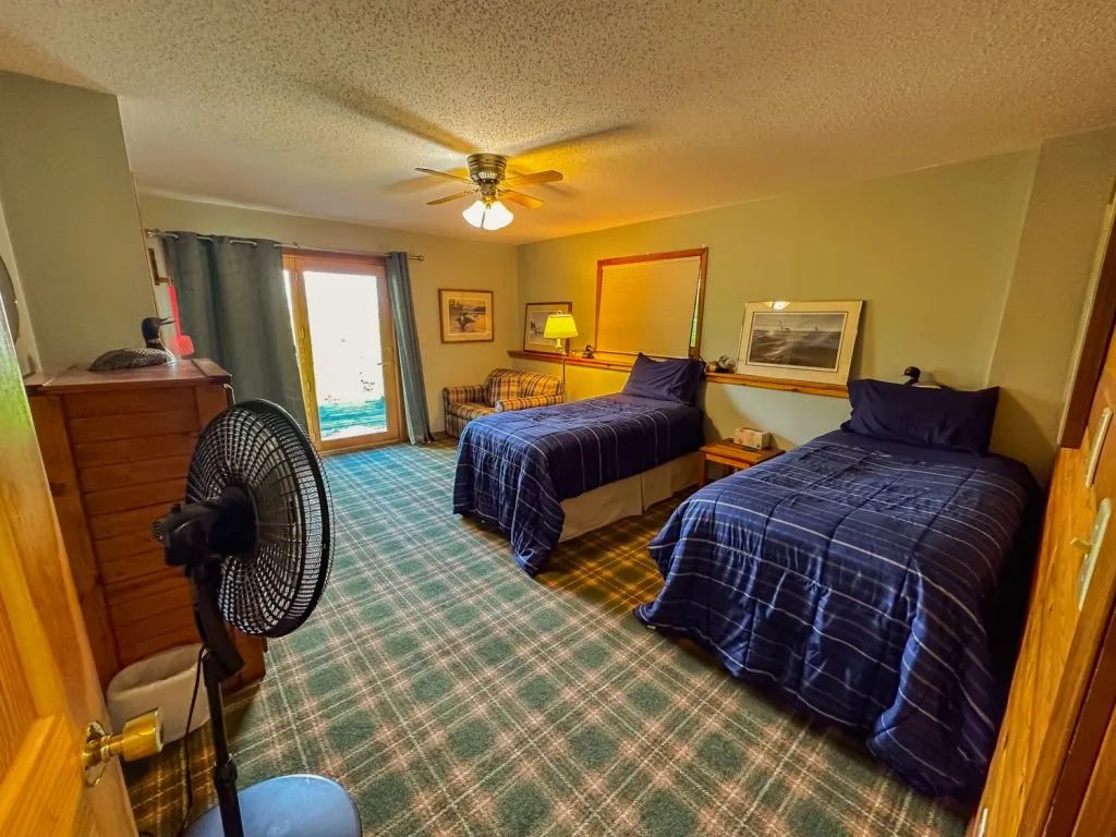 A bedroom with two beds and a fan in it.
