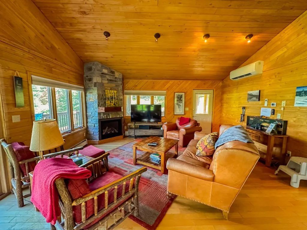 A living room filled with furniture and a fireplace in a log cabin.