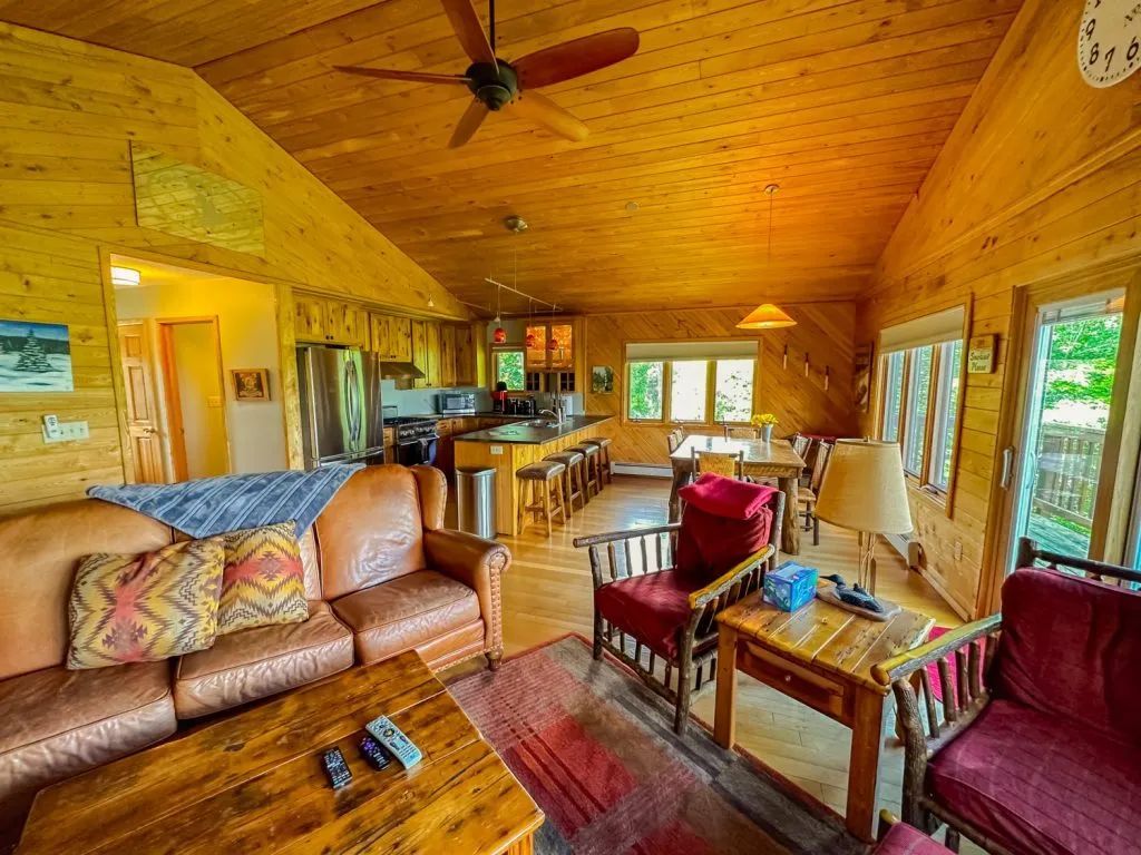 A living room filled with furniture and a ceiling fan in a log cabin.