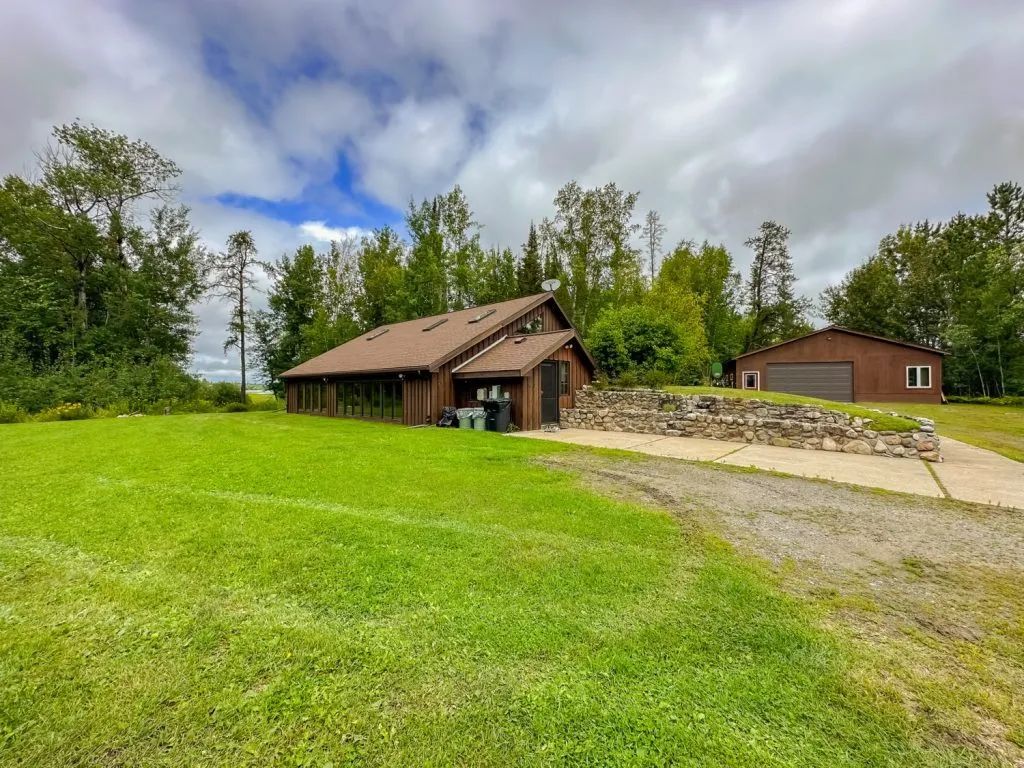 A house is sitting on top of a lush green field surrounded by trees.