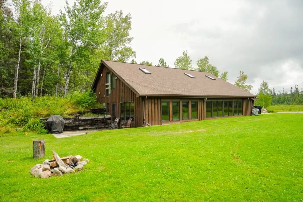 A large house is sitting in the middle of a lush green field.
