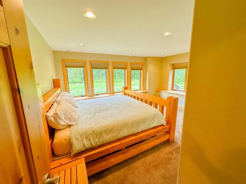A bedroom with a king size bed and lots of windows.