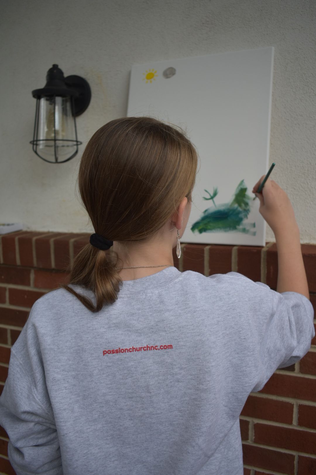A girl is painting a picture on a canvas