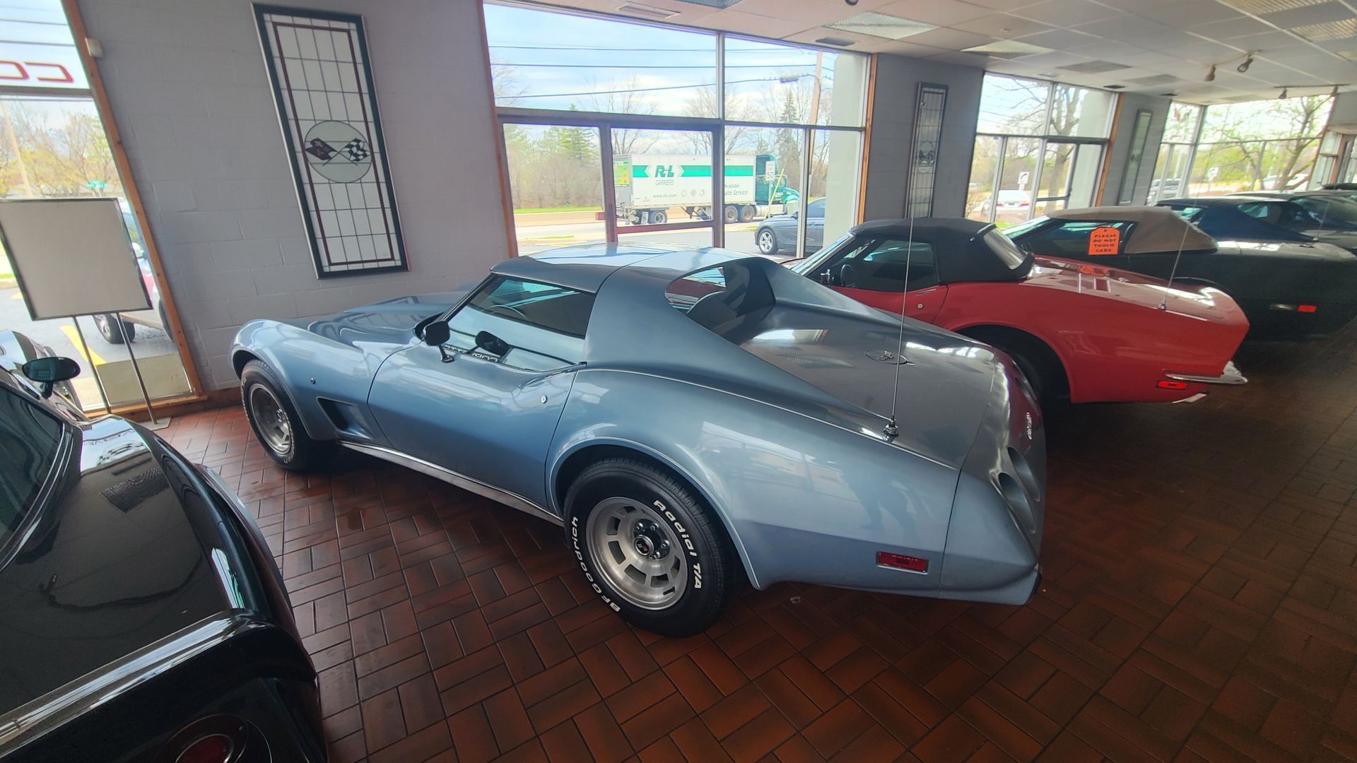 A row of cars are parked in a showroom.