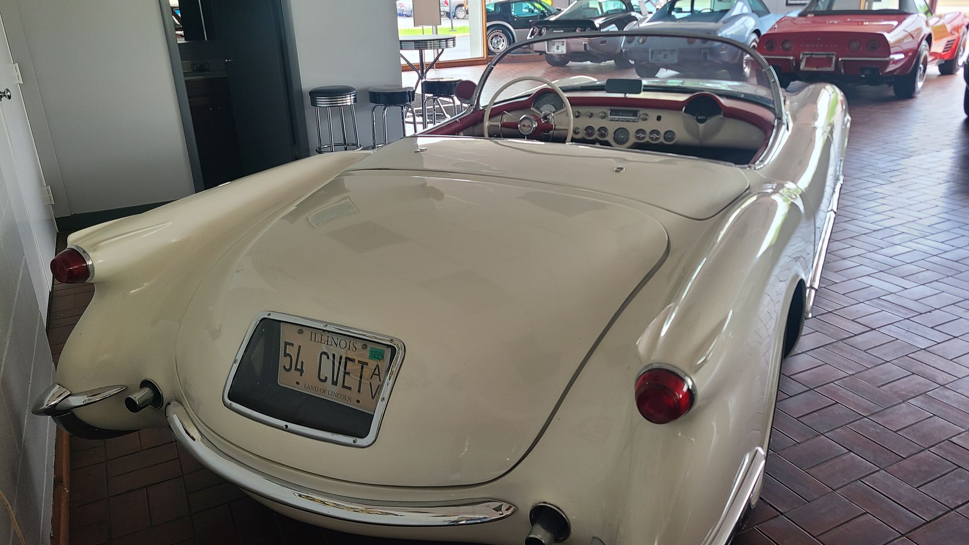 A row of cars are parked in a showroom.