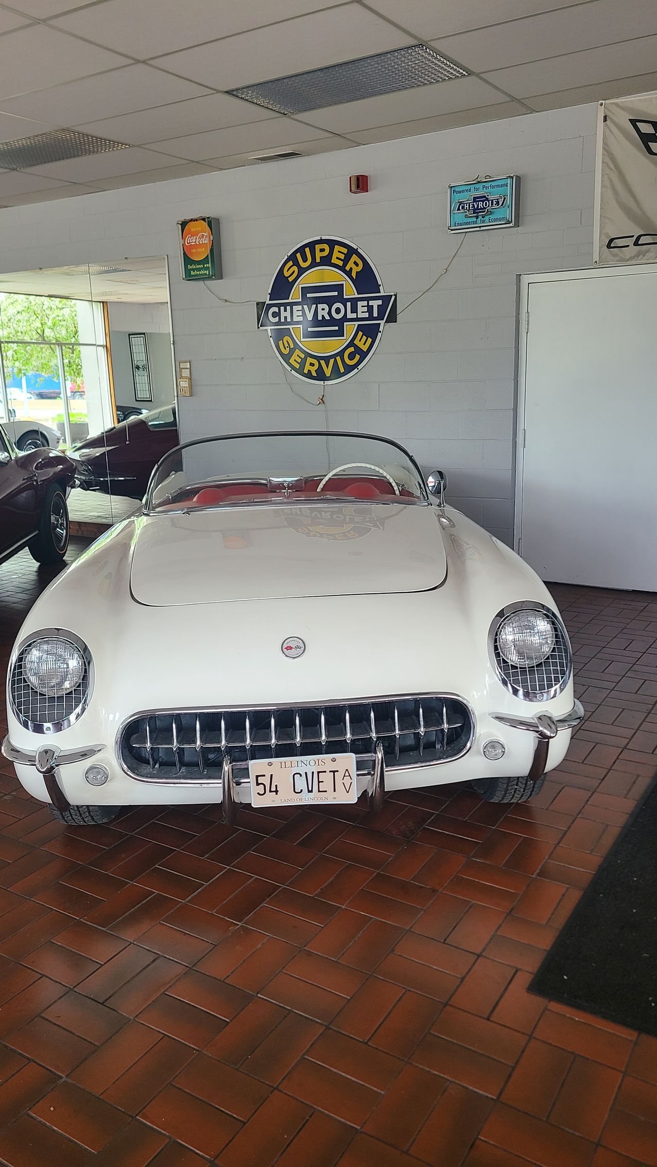 A blue corvette is parked in a showroom next to a black corvette.
