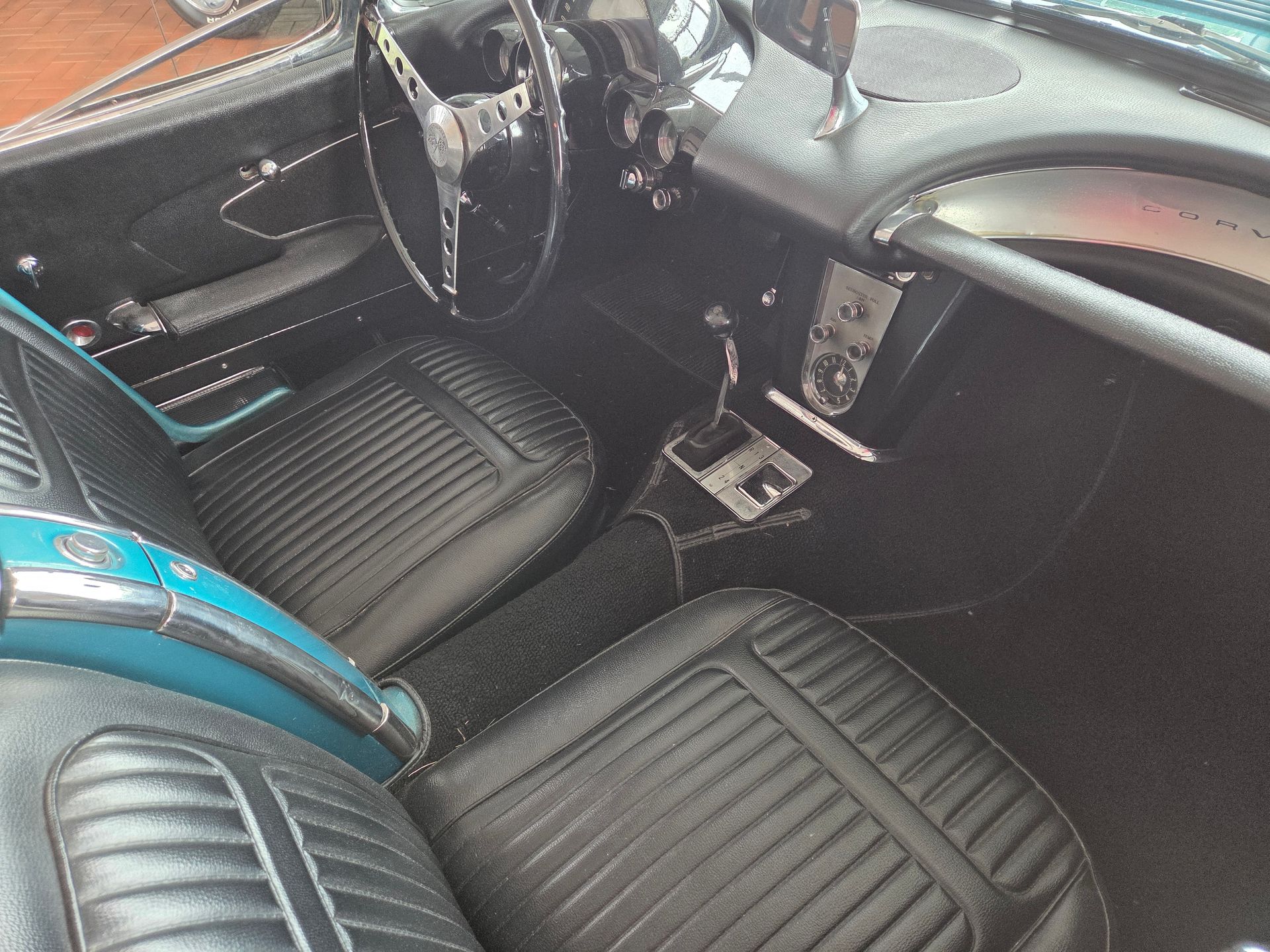 Black and turquoise car interior with striped seats, dashboard, steering wheel, and center console