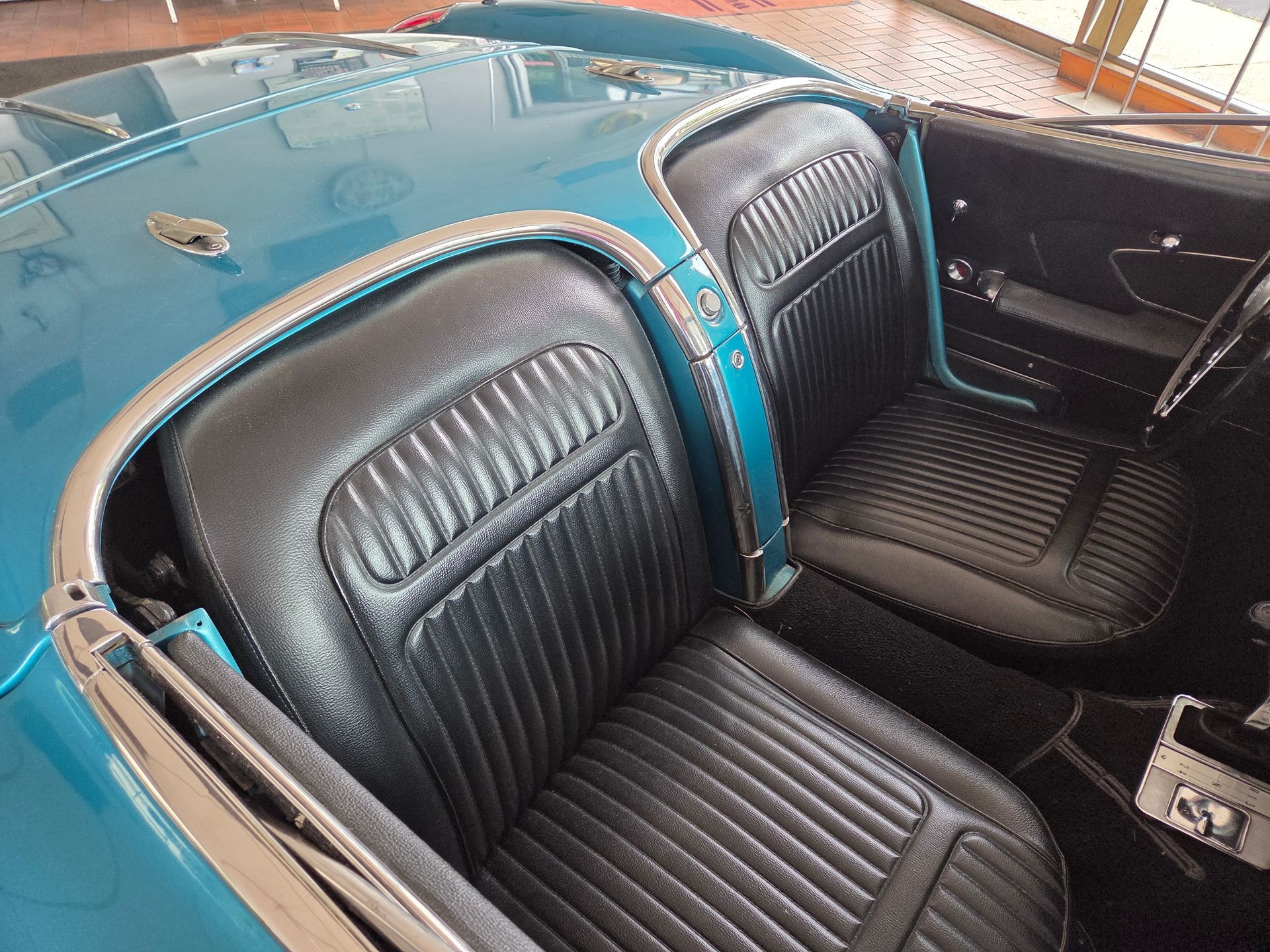 Blue vintage car interior with black ribbed leather seats and dashboard.
