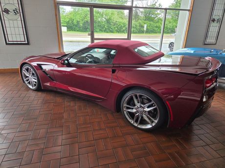 Maroon sports coupe parked on a brick floor in a covered garage with large windows. Maroon sports coupe parked on a brick floor in a covered garage with large windows.