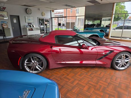 Red sports car in a showroom with blue cars and large windows. Red sports car in a showroom with blue cars and large windows.