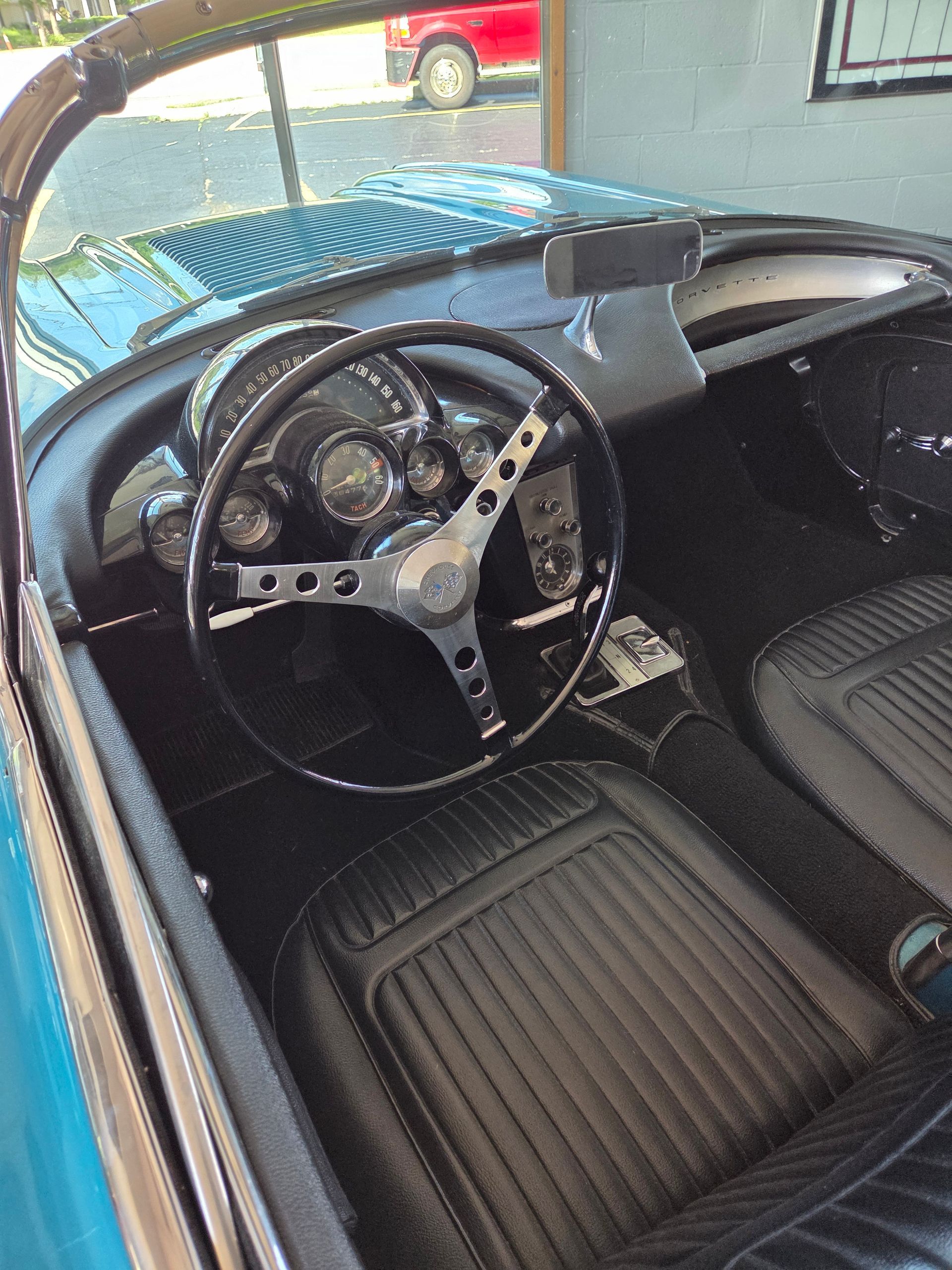 Interior of a vintage blue sports car with black seats and a wood-rim steering wheel