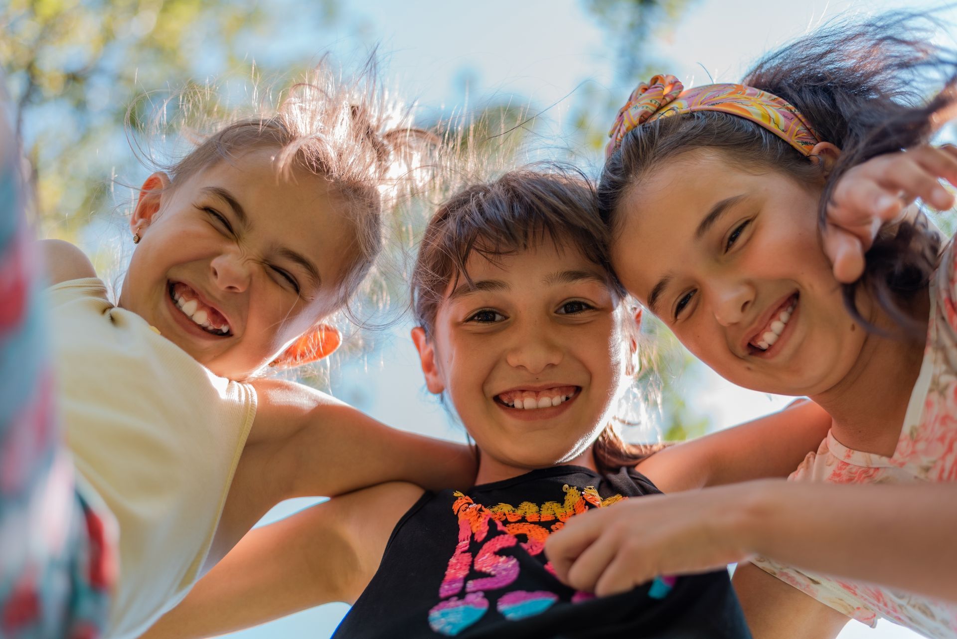 Three young children are hugging each other