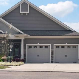Suburban house with gray siding and two-car garage, viewed from the driveway