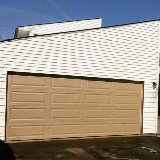 Tan garage door on a white house exterior