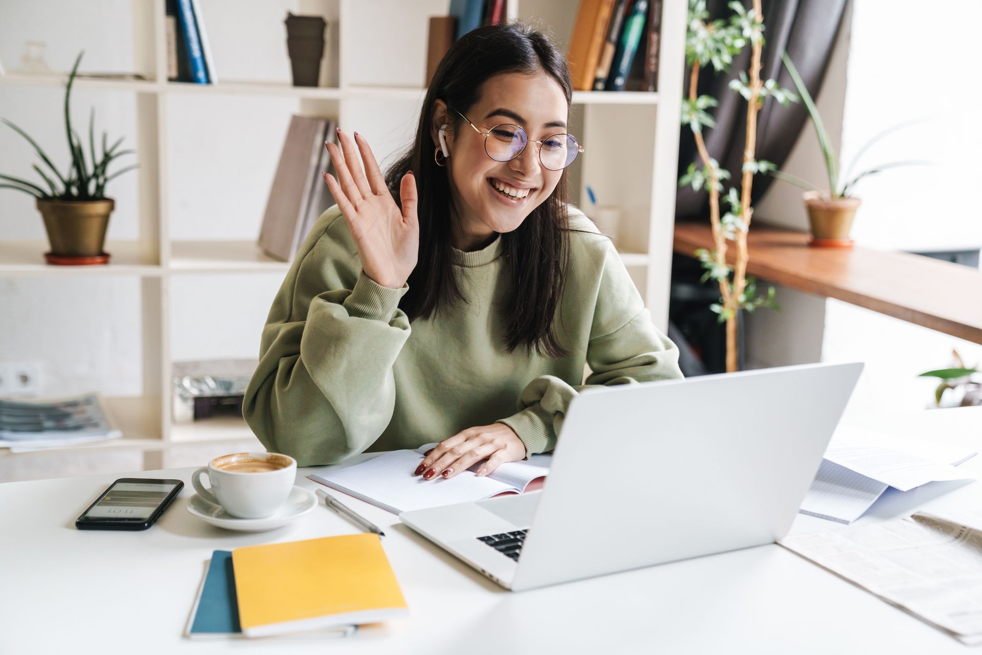 happy student waving in front of laptop