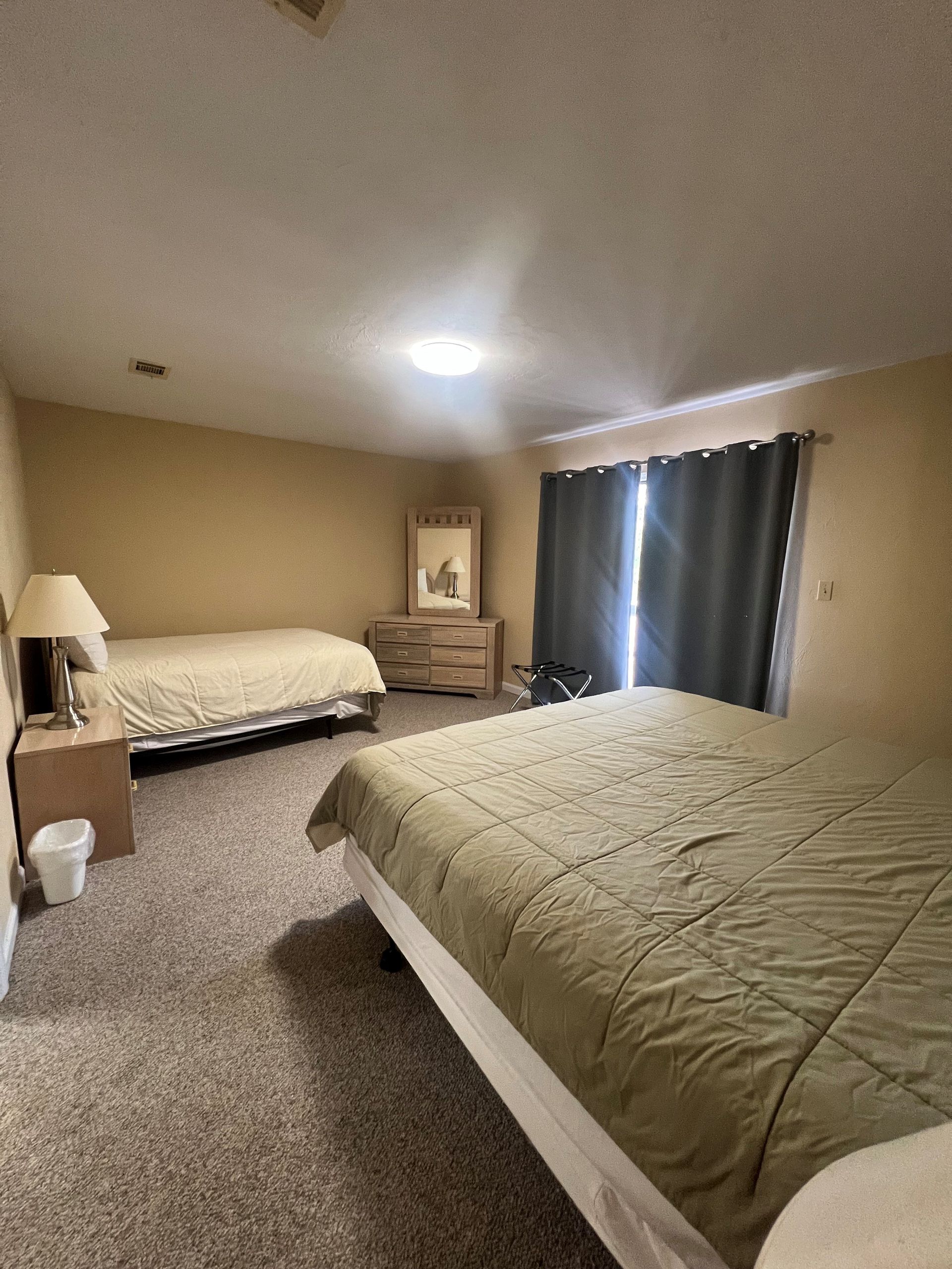 A bedroom with two beds , a dresser and a mirror.