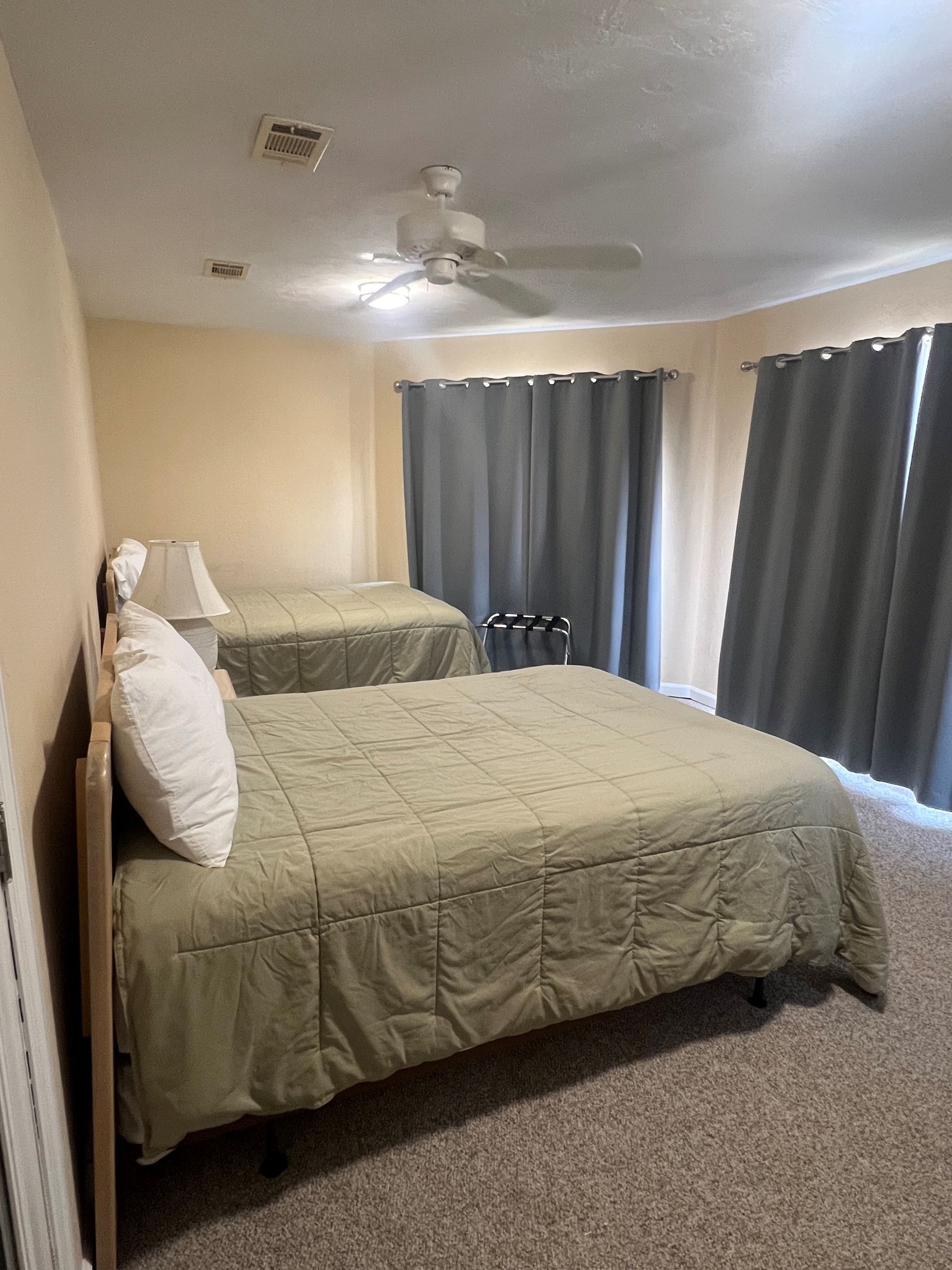 A bedroom with two beds and a ceiling fan.