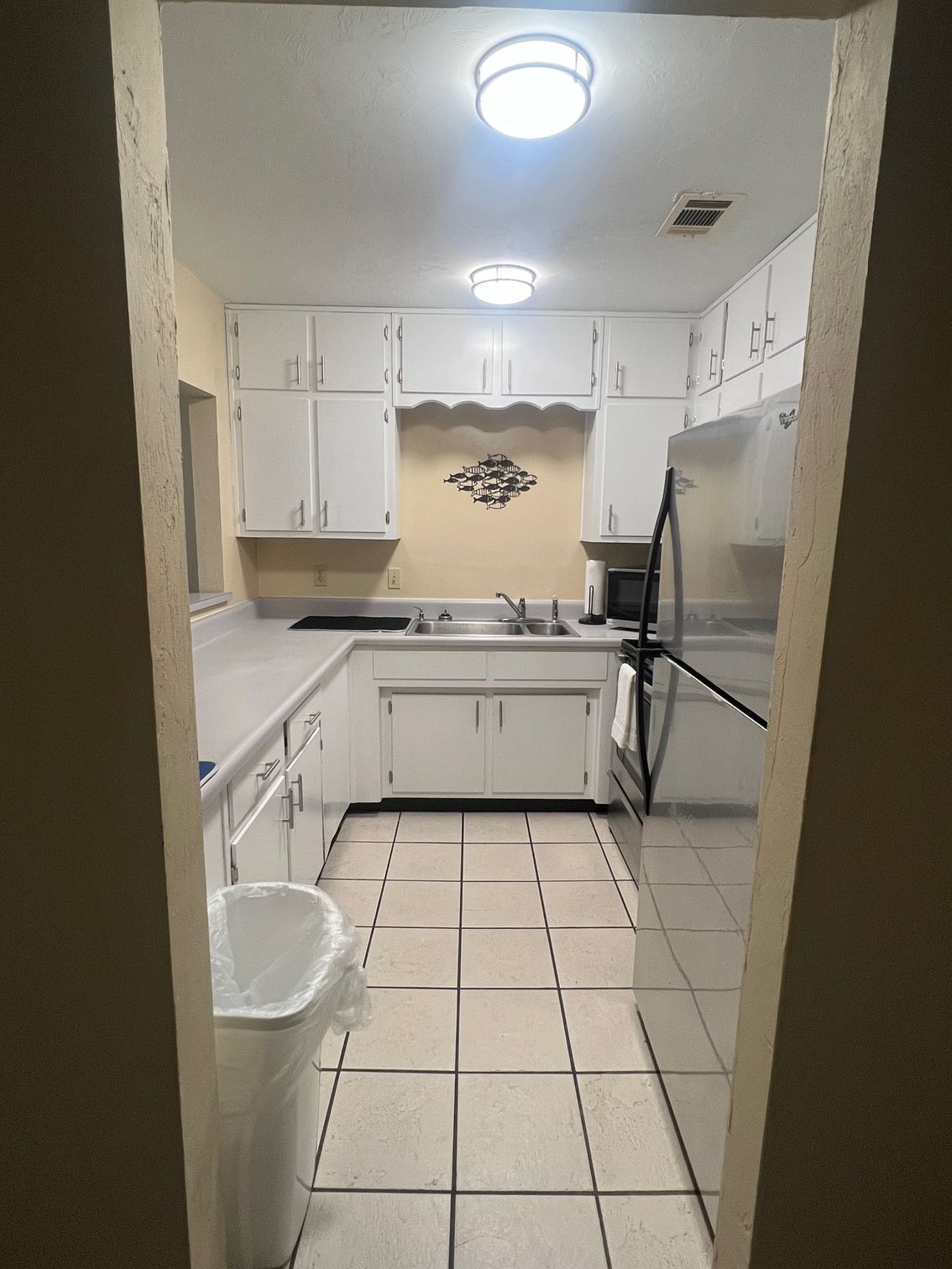A kitchen with white cabinets and a stainless steel refrigerator