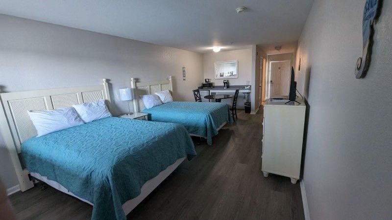 A hotel room with two beds , a desk and a television.