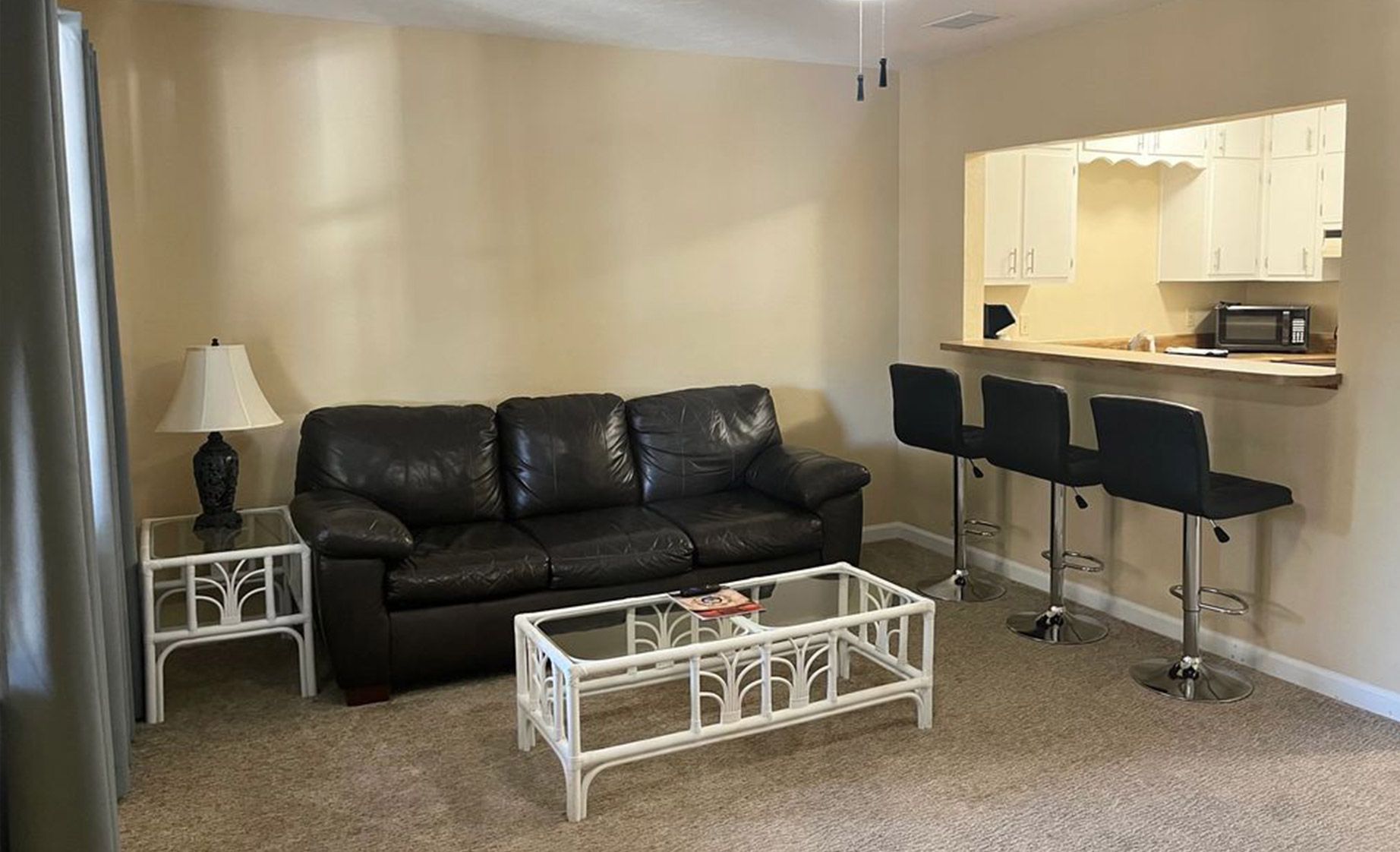 A living room with a couch , coffee table , and bar stools.