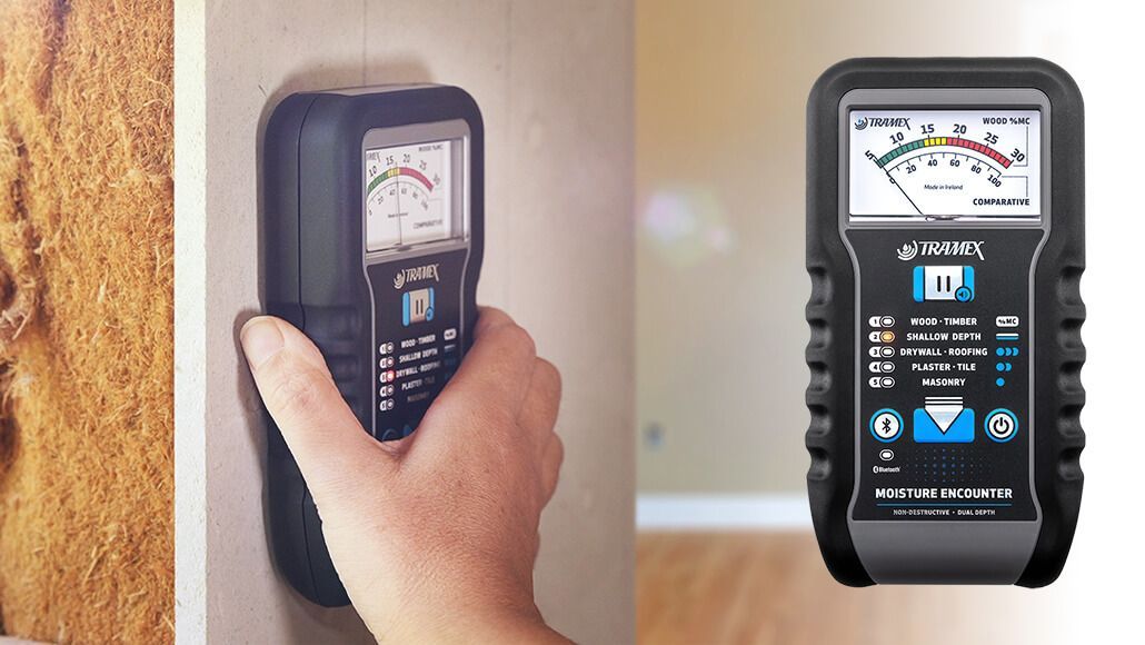 A person is using a moisture meter on a wall.