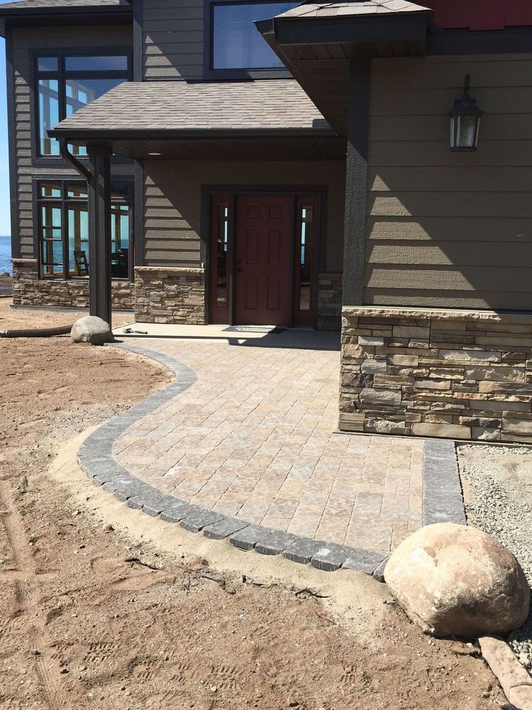 Stone walkway leading to a dark front entry on a house with stone and wood siding