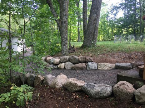Stone-bordered gravel path in a wooded park with tall trees and green foliage