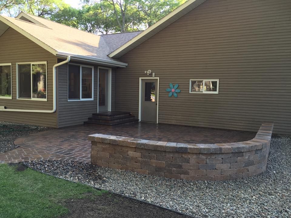 House exterior with a curved stone planter, gravel yard, and a small front porch area