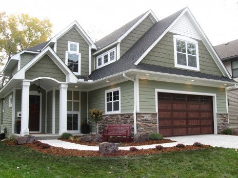 Gray two-story suburban house with green siding, white trim, and a red double garage door