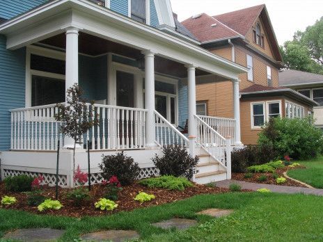 Two-story house with a white porch, blue siding, and a landscaped front yard.