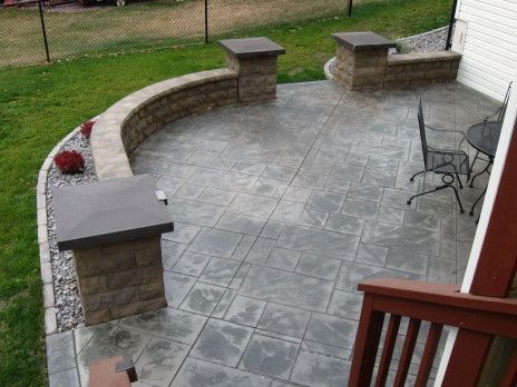 Curved stone patio with tiled floor, low walls, and patio chair beside a grassy yard