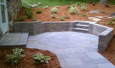 Curved stone patio with built-in retaining wall and small landscaped garden beds
