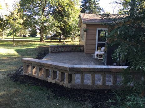 Wooden backyard deck beside a small shed, with trees and open lawn in the background.