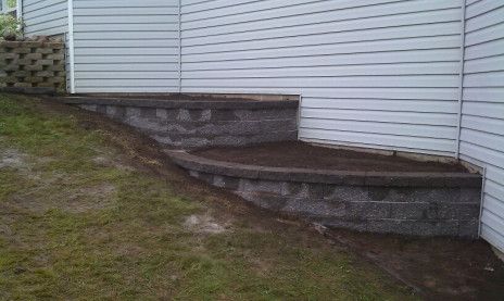 Weathered wooden steps leading up a grassy slope beside a white house wall