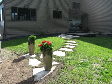 Backyard stone path with two potted plants leading to a patio doorway