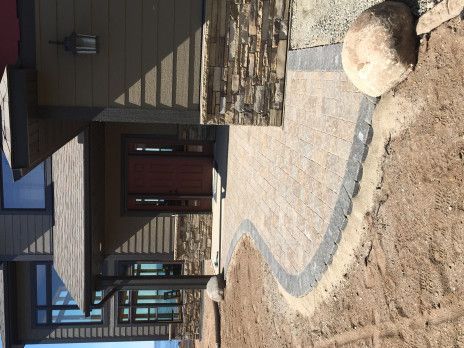 Modern house entrance with stone walkway, wooden front door, and landscaping under construction