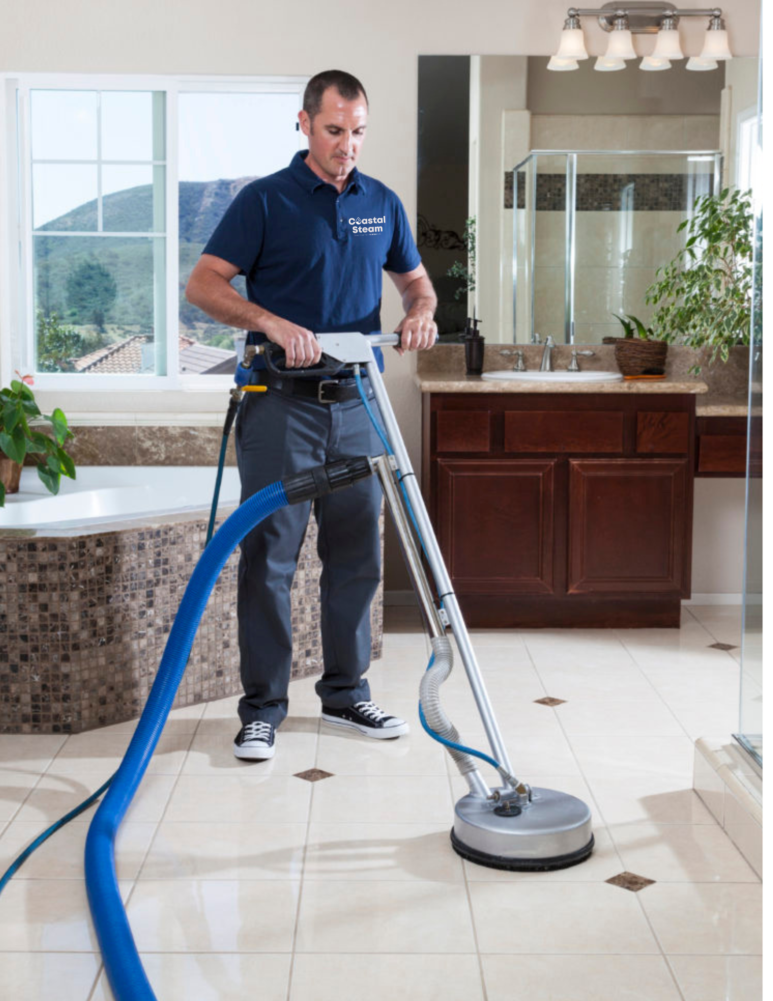 A bright yellow Kärcher vacuum cleaner sits on a tiled floor next to its coiled black hose and attachments.